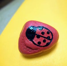 a rock with a ladybug painted on it sitting on top of a yellow surface