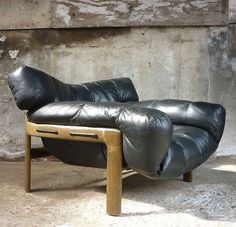 a black leather couch sitting on top of a wooden frame