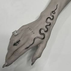 a woman's hand with a snake tattoo on it