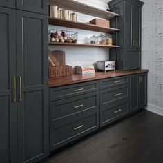 a kitchen with gray cabinets and wooden counter tops, along with baskets on the shelves