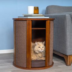 a cat sitting in the corner of a wooden cabinet next to a gray couch and coffee table