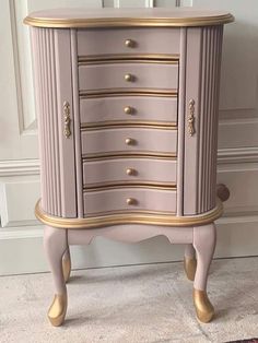 a pink dresser with gold trim and drawers