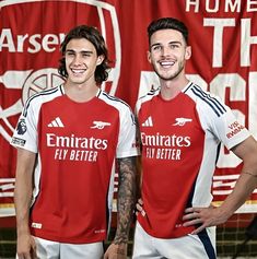 two young men standing next to each other in soccer uniforms