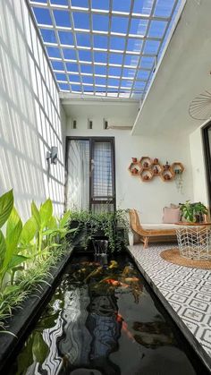 a room with a fish pond in the center and plants on the other side of the room