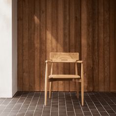 a wooden chair sitting on top of a tile floor next to a wooden paneled wall