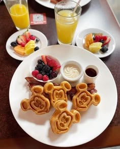 a white plate topped with breakfast foods next to glasses of orange juice and strawberries