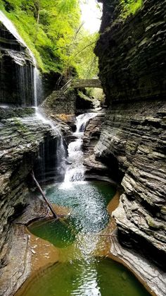 there is a small waterfall in the middle of this canyon with green water running down it