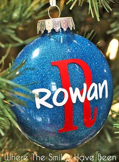 a blue ornament with the word rowan on it hanging from a christmas tree