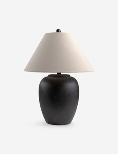 a black table lamp with a white shade on the base and a light bulb attached to it