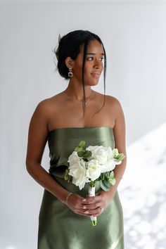 a woman in a green dress holding a bouquet of flowers