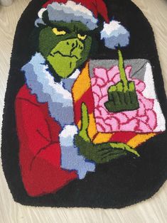 a rug with an image of the grinch holding a present and pointing at it