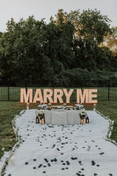 a sign that says marry me in front of some flowers and candles on the ground