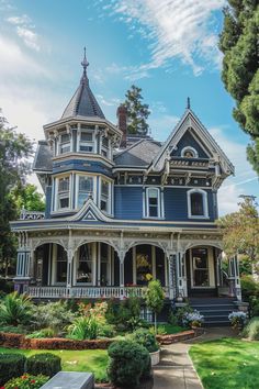 a blue victorian style house with white trim on the front porch and large garden area