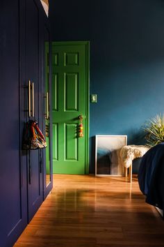 a bedroom with blue walls and wooden floors, green door in the corner next to bed