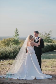 a bride and groom standing in front of the ocean