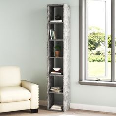 a living room with a white chair and a book shelf in front of a window