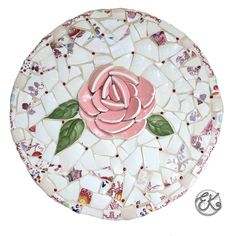 a pink rose is sitting on a mosaic plate