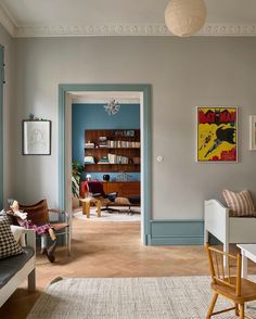 a living room filled with furniture and a book shelf next to a doorway that leads into a dining room