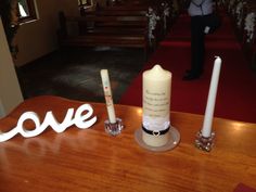 two candles are sitting on a table with the word love spelled in front of them