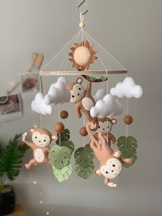 a baby mobile with monkeys hanging from it's sides and clouds in the background