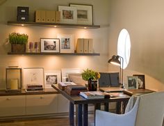 a desk with a laptop computer on top of it next to a chair and bookshelf