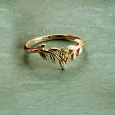 Olive Leaf Peridot Wishbone Ring in 9ct Yellow Gold | Gemondo – Gemondo UK Leaf Inspired Jewellery, Jewellery Inspired By Nature, Nature Inspired Ring, Cottagecore Rings, Cottagecore Wedding Ring, Peridot Aesthetic, Nature Engagement Rings, Peridot Ring Engagement, Nature Wedding Rings