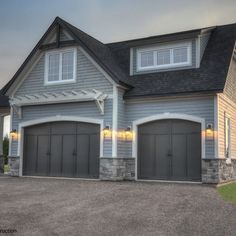 a large gray house with two garages on the front and one above it's doors