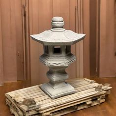 a small stone lantern sitting on top of a wooden pallet