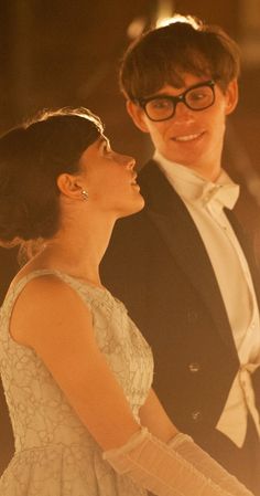 a man and woman standing next to each other in front of some lights on the ceiling