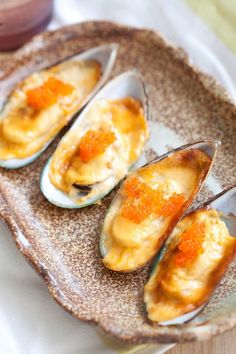 three open mussels on a plate with sauce