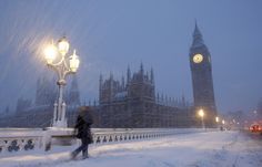 the big ben clock tower towering over the city of london covered in snow