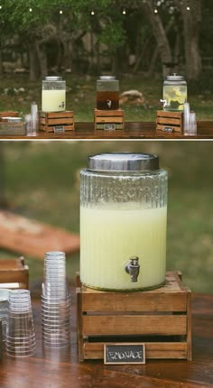 there is a large jar with some liquid in it sitting on a wooden table next to stacks of empty glasses