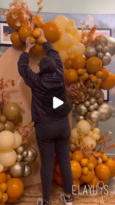 a person standing in front of a bunch of oranges and balloons on a wall