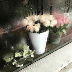 some flowers are sitting in a white vase on a window sill outside the house