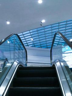 an escalator with two people riding down it in a large building next to stairs