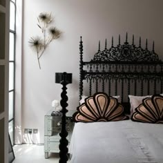 a bedroom with white walls and black iron bed frame in the center, along with decorative wall hangings