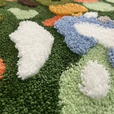 an area rug with various colors and shapes on the floor, including white flowers in center