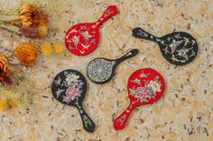 four paddles with flowers painted on them sitting next to dried flowers and pine cones