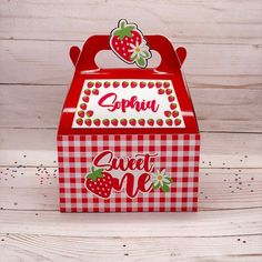 a red and white checkered box with strawberries on the top that says sweet one