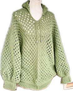 a green knitted sweater with holes on the front and back, sitting on a mannequin's head