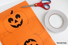 an orange piece of paper with two pumpkins cut out on it next to a pair of scissors