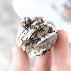 a hand holding a chocolate chip cookie with white icing