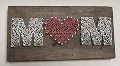 the word mom spelled with string art on a wooden plaque that says i love mom