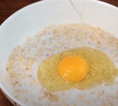 an egg being cooked in a bowl with oatmeal on the side,