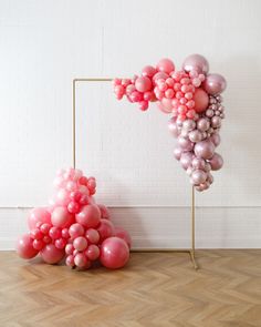 balloons are arranged in the shape of a letter on a wooden floor next to a white brick wall