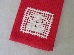 a red towel with white crochet on it sitting on top of a table