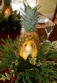 a pineapple centerpiece on a table with greenery and candles in the middle