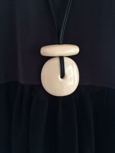 a black and white dress with a wooden necklace attached to it's neckline