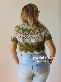 a woman is standing in front of a wall and looking at the back of her shirt