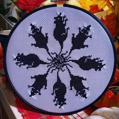 a cross - stitch pattern is shown on a table next to autumn leaves and pumpkins